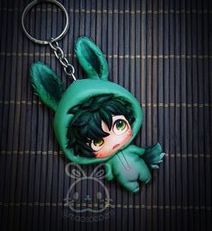 a keychain with an anime character wearing a green hoodie and bunny ears