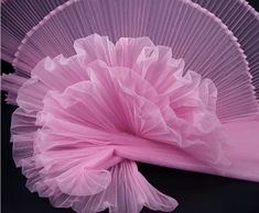 a large pink fan sitting on top of a table next to a black surface with a white cloth underneath it