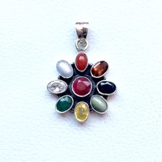 Genuine 925 Sterling Silver Navratan Pandent  Gemstone - Ruby , Emerald , Blue Sapphire, Yellow Sapphire, Hessonite, Cats Eye, Coral, Pearl, Cubic Zircona.  Stones setted - 9 pieces QTY - 1 piece in this listing. The navratna or nine gems influencing the nine planets are:  Ruby  =  Sun ,  Pearl = Moon, Red Coral = Mars, Emerald = Mercury,  Yellow Sapphire = Jupiter, zircon = Venus, Blue Sapphire = Saturn,  Hessonite = Rahu , Cat''s Eye = Ketu . Traditional Multi-stone Gemstones As Gift, Traditional Multi-stone Gemstones For Gifts, Sterling Silver Natural Stones Flower Pendant Jewelry, Sterling Silver Jewelry With Natural Stones In Flower Pendant, Sterling Silver Jewelry With Natural Stones Flower Pendant, Sterling Silver Flower Pendant With Natural Stones, Spiritual Multi-stone Oval Gemstones, Multicolor Spiritual Jewelry With Stone Setting, Multicolor Gemstone Oval Pendant Jewelry