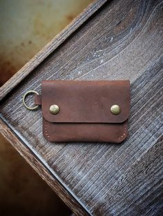 a brown leather wallet sitting on top of a wooden table next to a bottle opener