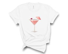 Cosmopolitan cocktail lovers t-shirt with cool graphic art print. White t-shirt with cool pink cocktail graphic art print. 100% soft, lightweight White cotton crewneck tee. Cosmo Cocktail lover shirt is available in sizes XS - 2XL (see photos for size chart). Custom printed, made to order. 100% Soft cottonLightweight fabricTear away labelRuns true to size (retail fit, unisex sizing, please see photo of size chart) Cocktail Tshirt, Cocktail Graphic, Cosmo Cocktail, Cosmopolitan Cocktail, Pink Cocktails, Tshirt For Women, Pink Cocktail, Pretty Colors, Drinking Shirts