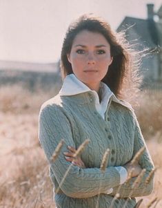 a woman standing in a field with her arms crossed