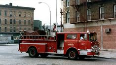 an old fire truck is parked on the side of the road in front of a brick building