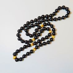 On offer is this beautiful Vintage 14kt. Yellow Gold Black Onyx Gemstone Necklace featuring large 10 mm Onyx Gems with large solid 14 karat yellow gold corrugated spacer beads. It measures a nice long 32 Inches in length with no clasp so it slips easily over your head. The lustrous and highly polished Onyx gems glow like glass and contrast nicely against the shiny 14 karat yellow gold beads. The necklace is hand knotted with black silk cord.  The 14kt yellow gold spacer beads measure a nice larg Elegant Long Necklace With Large Beads, Elegant Black Jewelry With 108 Beads, Elegant Black Necklaces With Large Beads, Elegant Black Polished Beads, Elegant Polished Black Beads, Formal Black Necklace With Gemstone Beads, Formal Black Jewelry With Large Beads, Formal Onyx Beaded Necklaces With Polished Beads, Luxury Black Pearl Necklace With Round Beads