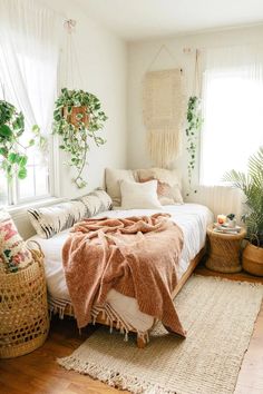 a bedroom with lots of plants in the window sill and blankets on the bed