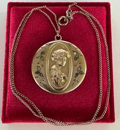 Rare and substantial antique circa 1900s Victorian era gold filled gibson girl portrait locket! This stunning pendant features a repousse woman's portrait facing to the right with ten clear paste stones, she's holding a flower with a green stone in the center. The locket hangs from its original chain. A phenomenal piece of fine Victorian jewelry, featuring a beautiful gibson girl!  ERA - Circa 1900s - Victorian  METAL / MATERIAL - Gold filled, rhinestone paste stones MARKINGS / HISTORY - Chain is marked Barrows 12k 1/15  (Barrows Jewelry is one of the oldest and most respected  jewelry stores in the country. They have been in business since 1851) CONDITION - Good antique condition. Gold filled metal has been polished & cleaned. Very little age appropriate patina & wear remains - a few mino Antique Medallion Locket Necklace Stamped 14k, Antique Yellow Gold Medallion Locket Necklace, Antique Style Yellow Gold Medallion Locket Necklace, Gold Engraved Jewelry For Vintage Events, Engraved Gold Jewelry For Vintage Events, Antique Cameo Yellow Gold Jewelry, Cameo Medallion Locket Necklace, Antique Cameo Medallion Jewelry, Victorian Yellow Gold Medallion Locket Necklace