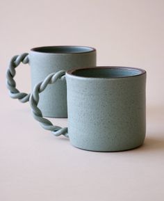 two blue mugs sitting next to each other on a table