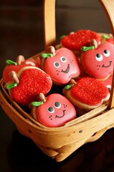 some little red apples in a basket with strawberries on them and smiling faces drawn on them