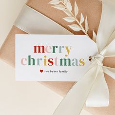 a gift wrapped in brown paper with a white ribbon and merry christmas card on top