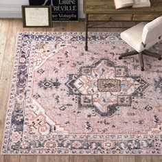 a large rug with an ornate design in pink, blue and beige colors on a wooden floor