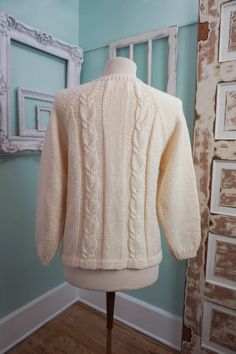 A classic women's cardigan sweater, in a soft ivory white acrylic. It has a unique wide pattern of traditional cable knit down the front. It closes up the front with a row of really unique swirly plastic buttons. The sweater is soft and comfy, not stiff at all. No damage or issues. Please check measurements carefully. Condition: Very Nice Vintage Tag: 100% Acrylic Size L Measurements in inches.... Length: 23.5 Chest: 19 ✩ Because you don't want to miss a thing, follow @heartkeyologie on Facebook Cream Cable Knit Crew Neck Outerwear, Cream Fitted Knitted Sweater, Classic White Textured Knit Cardigan, Fitted Cream Knitted Sweater, Classic Crew Neck Cable Knit Cardigan, Classic Beige Cable Knit Cardigan, Classic Cream Knitted Cardigan, Classic Cream Cable Knit Cardigan, Classic Knitted Cream Cardigan