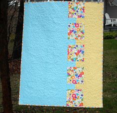 a blue and yellow quilt hanging from a clothes line