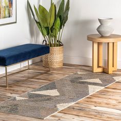 a living room with wooden floors and a blue bench next to a plant in a pot