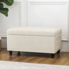 a white bench sitting on top of a wooden floor next to a potted plant