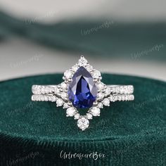 a blue and white diamond ring sitting on top of a green velvet box