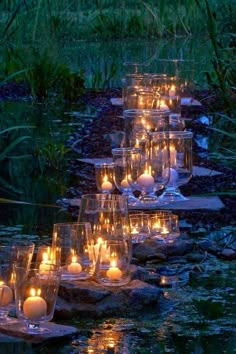 many candles are lit on the rocks in the water