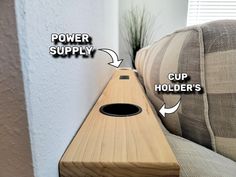 a close up of a wooden object on a couch near a wall with the words power supply and cup holder's