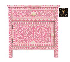 a pink and white chest with an intricate design on the front, two drawers and one door