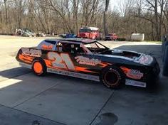 an orange and black race car parked in a parking lot