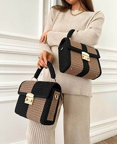 a woman holding two handbags in her hands and standing next to a white wall