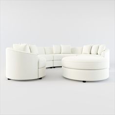 a large white sectional couch sitting on top of a white floor next to a round ottoman