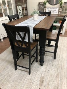 a dining room table and chairs in front of a white wall with a mirror on it