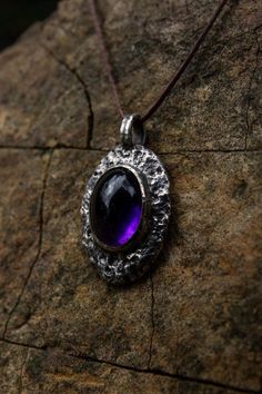 Introducing a unique handcrafted pendant that evokes the essence of a lost archaic era, this raw silver amethyst piece brings an earthy, rustic charm with a distinct medieval inspiration. The organic, textured silver frame encircles a captivating deep violet amethyst, reminiscent of a relic unearthed from ancient times. Each detail reflects the dedication to capturing the beauty of imperfection, allowing the natural elements to speak for themselves. The silver's raw finish gives the pendant an a Purple Amulet Necklaces As Gifts, Purple Amulet, Amethyst Amulet Necklace For Meditation, Handmade Amethyst Amulet Crystal Necklace, Purple Amethyst Amulet Jewelry, Dark Amethyst, Protection Amulet, Raw Beauty, Spiritual Connection