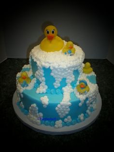 a blue and white cake with rubber ducks on it