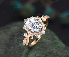 a gold ring with an oval cut diamond surrounded by smaller round diamonds on a green rock