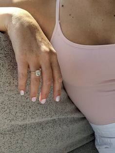 a woman wearing a ring on her left hand sitting on a couch with the rest of her arm behind her back