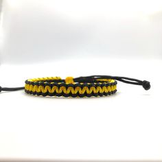 a yellow and black paracorine bracelet on a white background