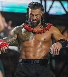 a man with long hair and tattoos on his chest wearing a red lei around his neck