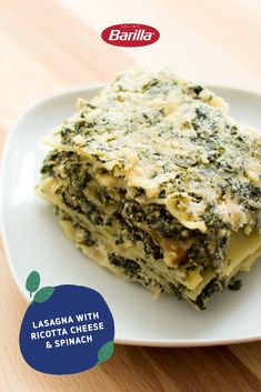 lasagna with ricotta cheese and spinach on a white plate over a wooden table