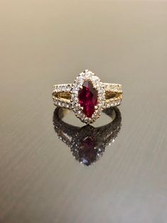 "DeKara Designs Collection Metal- 18K Yellow Gold, .750. Stones- Marquise Ruby Center Beautiful Red Color 1.07 Carats. 16 Round Diamonds F-G Color VS2 Clarity, 1.15 Carats. This is a halo setting with a magnificent marquise ruby set in the center surrounded by 48 round diamonds in a \"U\" pave setting, and features a split shank. The marquise ruby is 1.07 carat with an beautiful hue of red in color. Rubies are the rarest of fine gemstone! The side stones are all F-G in color and VS2-SI1 in clari Wedding Ruby Ring With Vvs Clarity Marquise Cut, Marquise Cluster Ring With Accent Stones For Wedding, Luxury Marquise Ruby Gold Jewelry, Gold Marquise Wedding Ring With Accent Stones, Dazzling Oval Ruby Wedding Ring, Gold Marquise Ring With Accent Stones, Luxury Ruby Birthstone Ring For Wedding, Exquisite Gold Marquise Cut Ring, Gold Marquise Birthstone Ring With Accent Stones