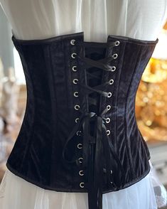 Transform your look with the Bious Corset. Made with luxurious black velvet, this overbust corset will enhance your curves and give you a confident, alluring silhouette. Elevate your style and make heads turn with this must-have fashion staple. The Bious Corset Gorgeous Black Velvet Over Bust Corset. Velvet lined with cotton and steel boned. Front metal busk Opening and back lacing with white satin ribbon. The center front length is 14.5" and back length 13".New colors added Black satin.Sizes X- Elegant Black Corset Belt With Boned Bodice, Elegant Corset With Boning For Costume Party, Gothic Formal Corset With Boned Bodice, Black Strapless Corset Belt For Evening, Gothic Boned Bodice Corset For Formal Occasions, Black Corset Belt With Boning For Parties, Black Overbust Corset Belt For Evening, Elegant Overbust Corset Belt For Costume Party, Elegant Black Corset Dress With Boning