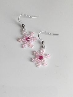 Little pink snowflakes made out of Miyuki glass beads with a Swarovski crystal bead in the centre for a bit of extra sparkle.  Hung on 302 stainless steel ear wires. Handmade Pink Crystal Earrings, Pink Beaded Dangle Earrings With Bead Caps, Pink Dangle Beaded Earrings With Bead Caps, Pink Beaded Earrings With Bead Caps As Gift, Pink Sparkling Crystal Earrings Gift, Pink Sparkling Crystal Earrings For Gift, Snowflake Earrings, Swarovski Crystal Beads, Earrings Pink