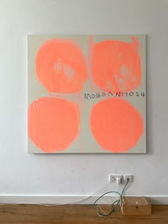 an orange and white painting hanging on the wall next to a light switch in a room