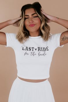 a woman wearing a white crop top with the words last ride for the bride printed on it