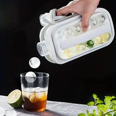 a person is pouring ice into a glass with lemons and limes in it