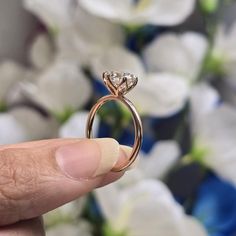 a close up of a person's hand holding a ring with a diamond on it