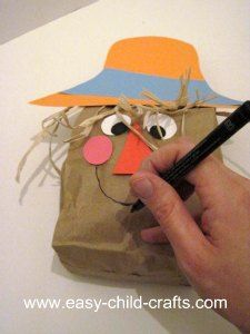 a hand holding a pen over a paper bag with an image of a scarecrow on it