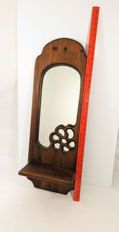 a wooden mirror sitting on top of a shelf next to a ruler