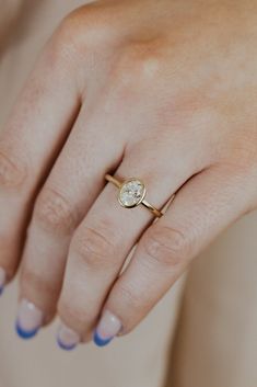 a woman's hand wearing a gold ring with a diamond on the middle finger