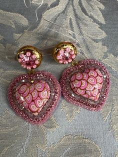 These adorable hearts are made with pink and gold swirls surrounded with tiny cut crystals and rhinestone chain and tiny seed beads they make the cutest accessories to any outfit approx 2.5 inches long and 1.5 inches wide I only use hypoallergenic stud earrings Pink Dangle Beaded Earrings For Valentine's Day, Whimsical Pink Beaded Earrings, Pink Heart Beads Jewelry For Party, Pink Heart Beads Dangle Jewelry, Pink Heart Beaded Earrings For Gifts, Pink Beaded Earrings With Heart Beads As Gift, Pink Heart Beads Beaded Earrings For Gift, Gold Embellished Earrings Gift, Pink Heart-shaped Beaded Earrings For Parties