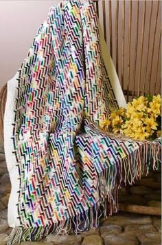 a blanket draped over a chair with flowers in the foreground and yellow daffodils in the background