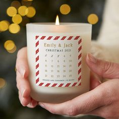 a person holding a candle with a calendar on it in front of a christmas tree