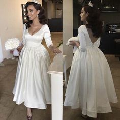 a woman in a white dress standing next to a mirror