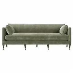 a green velvet couch with two pillows on the back and one arm upholstered