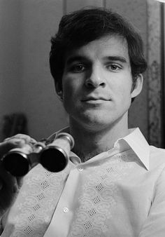 a black and white photo of a man holding two binoculars in front of his face