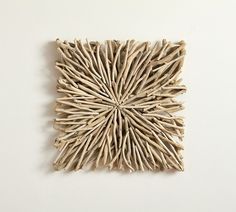 a piece of art made out of sticks on a white surface with no one around it